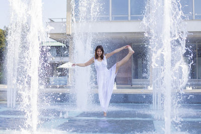 Mature woman enjoying splashing fountain in city