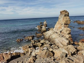 Rock formation on beach against sky