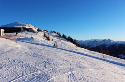 Scenic view of skiing area against clear blue sky during winter 