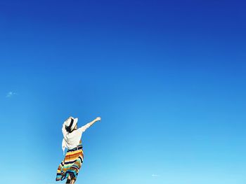 Rear view of woman standing against blue sky