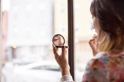 Woman applying make-up while sitting in bar