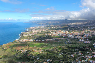 Aerial view of townscape by sea against sky