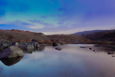 Scenic view of river and mountains against blue sky