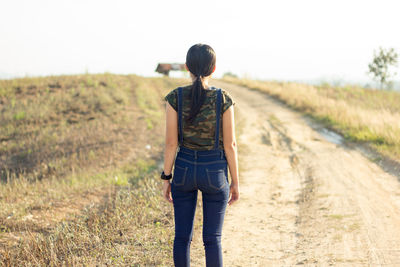 Rear view of woman standing on dirt road