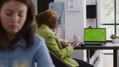 Side view of young woman using laptop at home