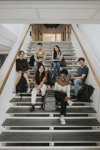 Cheerful multiracial male and female students sitting on steps at university