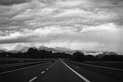 Country road against cloudy sky