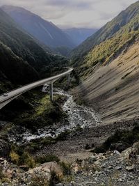 Scenic view of stream by mountains against sky