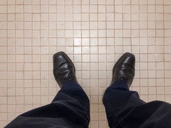 Low section of man standing on tiled floor