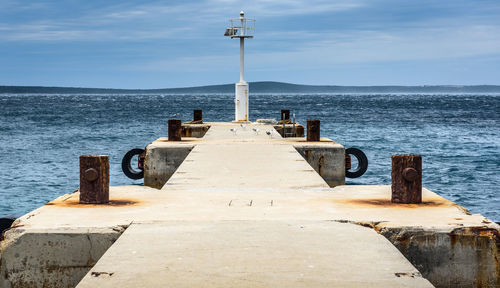 Jetty leading towards sea against sky