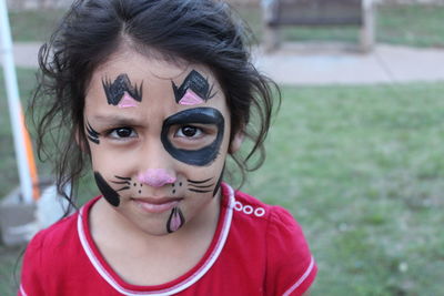 Portrait of girl with face paint on field at yard