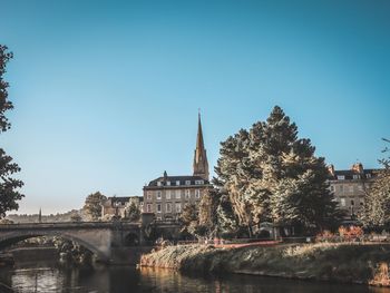 Bridge over river amidst buildings against clear sky