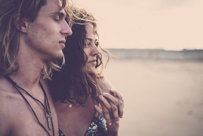 Close-up of young couple standing at beach