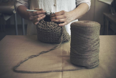 Midsection of woman knitting purse at home