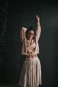 Portrait of young woman standing against wall