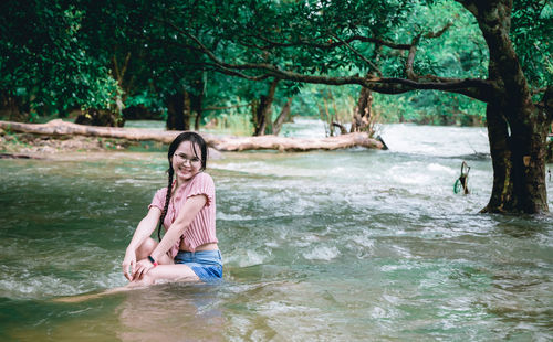 Portrait of smiling young woman against trees