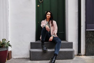 Portrait of woman sitting on entrance of building