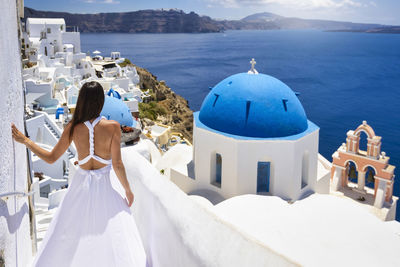 Rear view of woman looking at sea by buildings