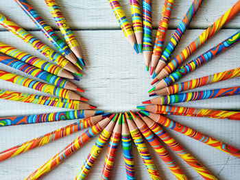 Circle of colored pencils on white wooden background