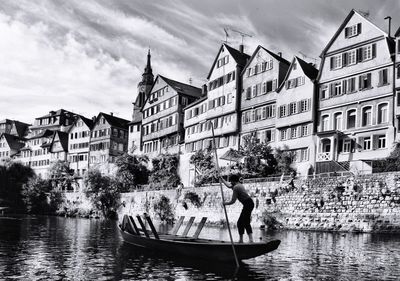 People in boat sailing on river against buildings