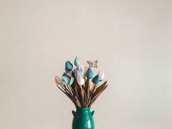 Close-up of artificial butterfly and flowers in vase against white background