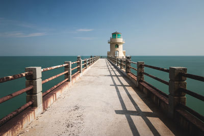 Lighthouse by sea against sky