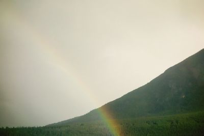 Scenic view of rainbow over mountain against sky
