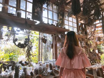 Rear view of woman standing in garden shed