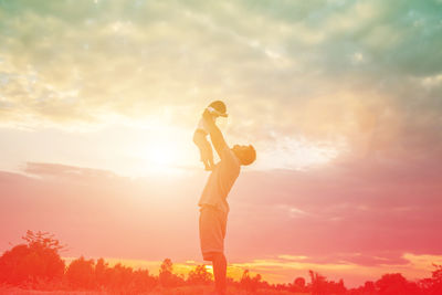 Side view of man standing against orange sky