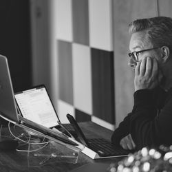 Midsection of man working from home using mobile phone and laptop while sitting table