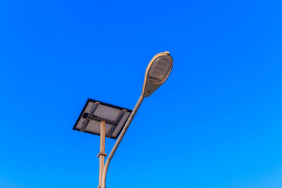 Low angle view of electric lamp against blue sky