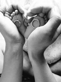 Cropped hands of person holding baby legs and rings
