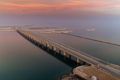 Bridge over sea against sky during sunrise, king fahd causeway is known as khobar bahrain bridge.