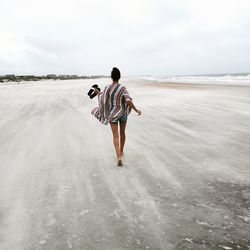 Full length rear view of woman walking at beach