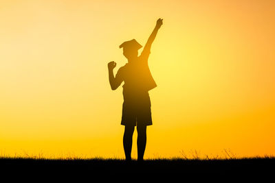 Silhouette man standing on field against sky during sunset