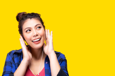 Portrait of smiling young woman against yellow background