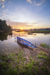 Sailboats moored on lake against sky during sunset