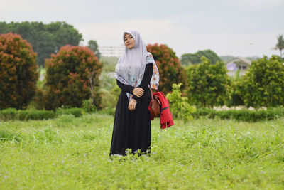 Portrait of smiling woman in hijab standing on field 