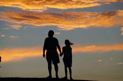 Silhouette of father and daughter at dusk