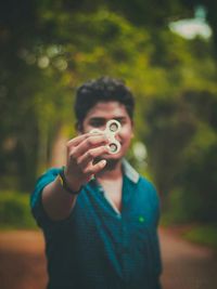Young man holding fidget spinner at park