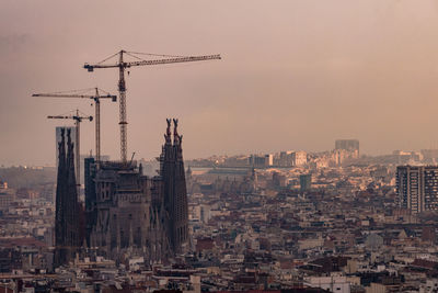 Cranes in city against clear sky