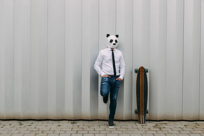 Full length portrait of person standing against wall