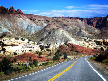 Road by mountains against sky