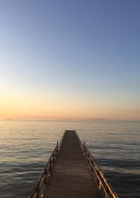 Pier over sea against sky during sunset