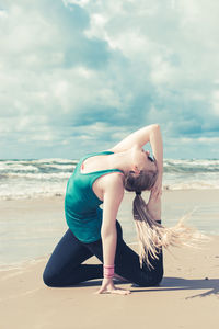 Midsection of woman at beach against sky