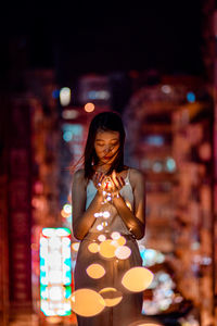 Young woman in illuminated string light