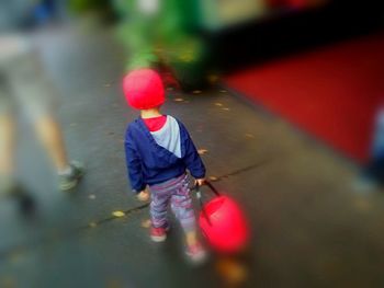 Rear view of man walking with red umbrella