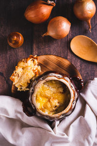 Homemade onion soup with cheese croutons in a pot on the table top and vertical view