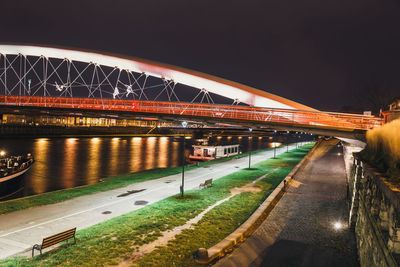 Illuminated bridge over river in city against sky at night