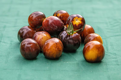 Fresh cherry tomatoes of different varieties on the green background, close-up